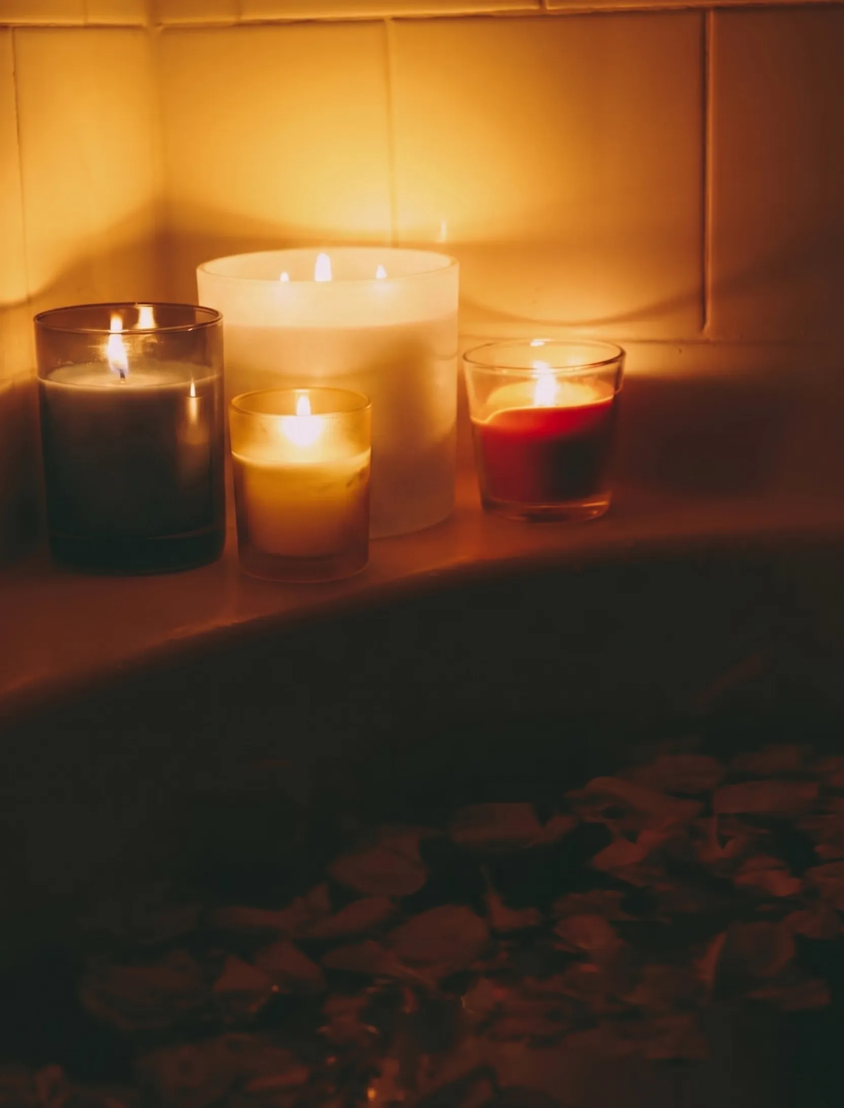 A candlelit bath with candles and bath accessories set out for a soak.