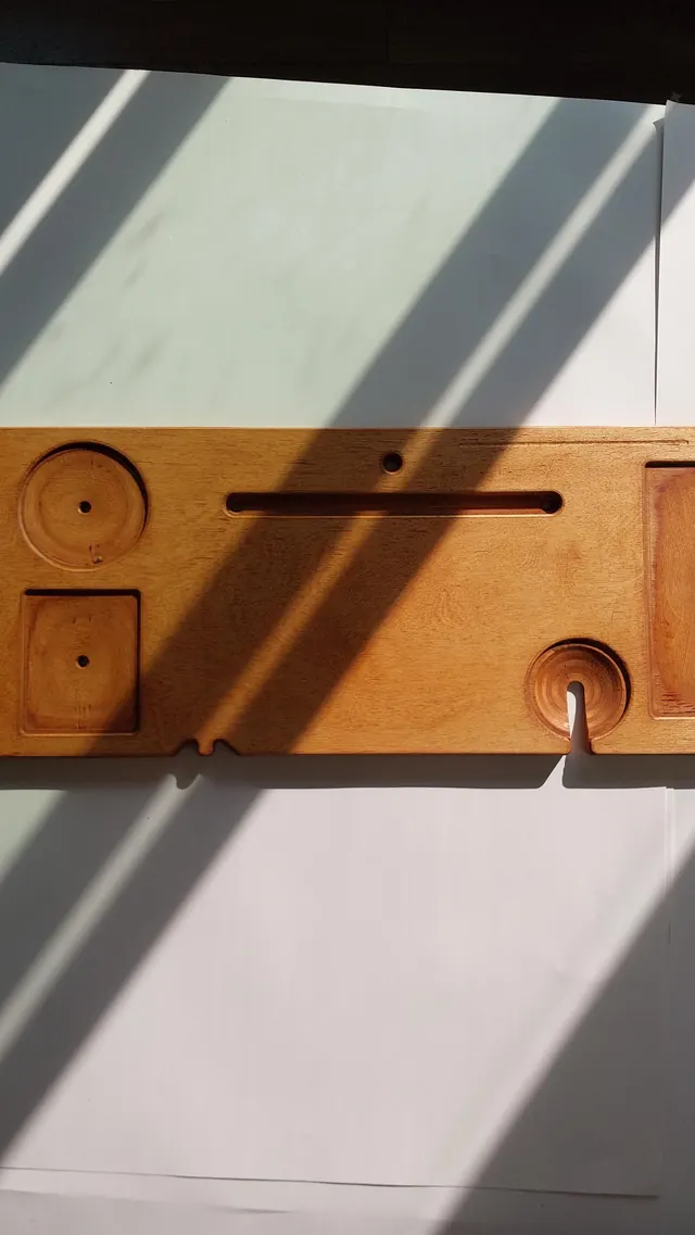 The full board seen from above in a warm honey finish: the round candle holder and square tray at one end, the long tablet groove down the middle, and the wine notch at the other.