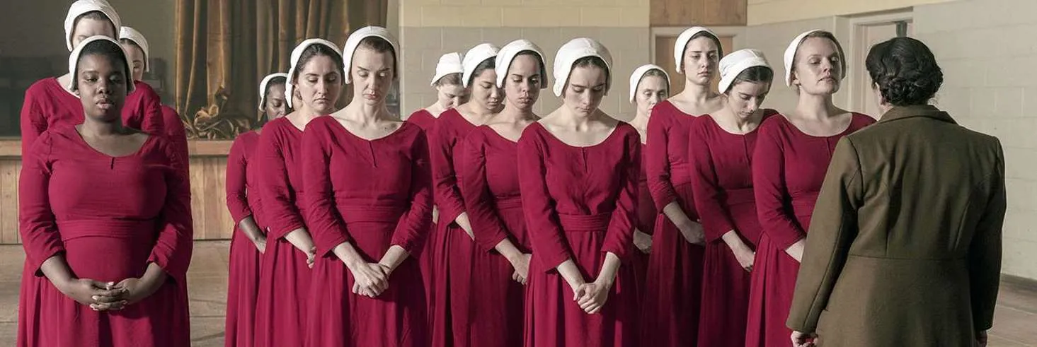 Handmaids in red robes and white bonnets standing in rows in The Handmaid's Tale